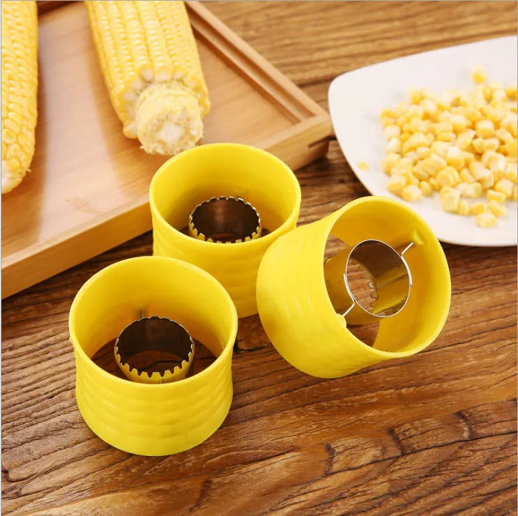 Yellow manual corn grinder thresher with corn-shaped PP handle on a kitchen counter.