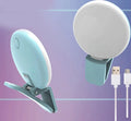Small round clip-on LED fill light attached to a mobile phone, shown in four colour options.