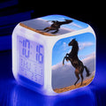 Small square cartoon-style LED alarm clock showing time, temperature, and week day on its display.