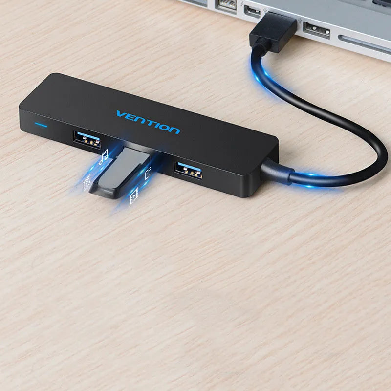 Black USB 3.0 hub with four ports and a short cable on a desk