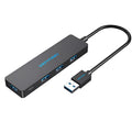 Black USB 3.0 hub with four ports and a short cable on a desk