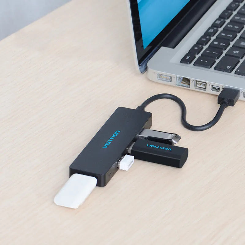 Black USB 3.0 hub with four ports and a short cable on a desk