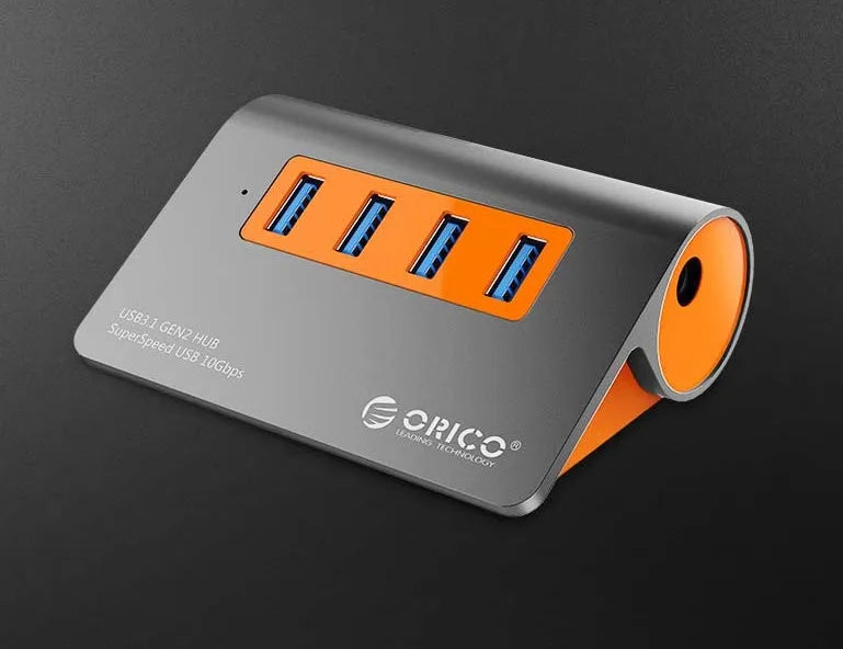 Dark grey and orange aluminium USB-C laptop docking station with four USB 3.1 ports and a separate data cable.