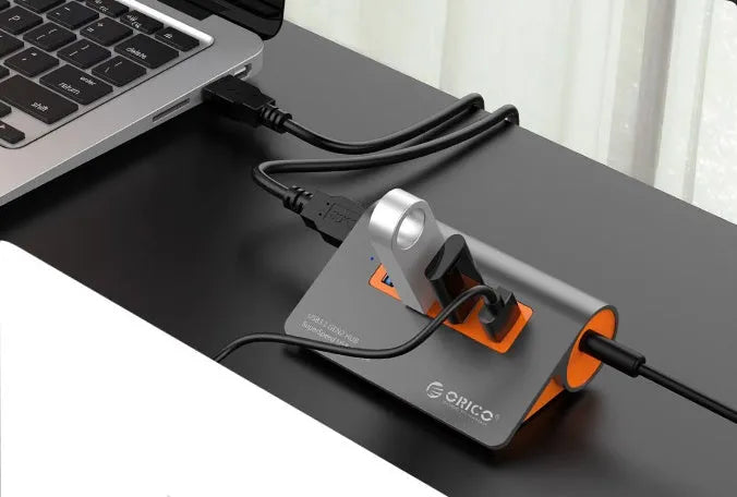 Dark grey and orange aluminium USB-C laptop docking station with four USB 3.1 ports and a separate data cable.