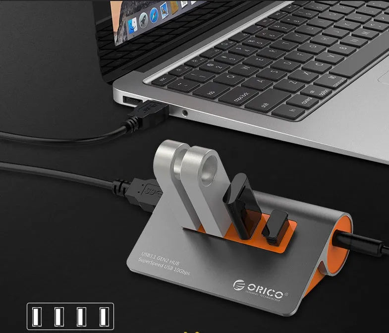 Dark grey and orange aluminium USB-C laptop docking station with four USB 3.1 ports and a separate data cable.