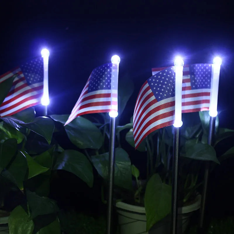 Solar-powered garden flag light showing American flag design on waterproof fabric with stainless steel pole