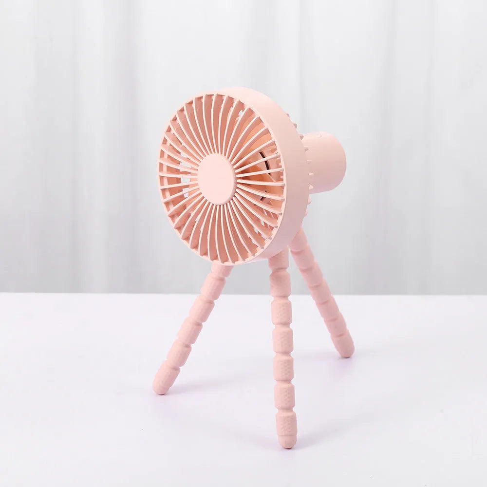 Black USB rechargeable desk fan with flexible tripod legs and an adjustable bending head on a wooden desk.