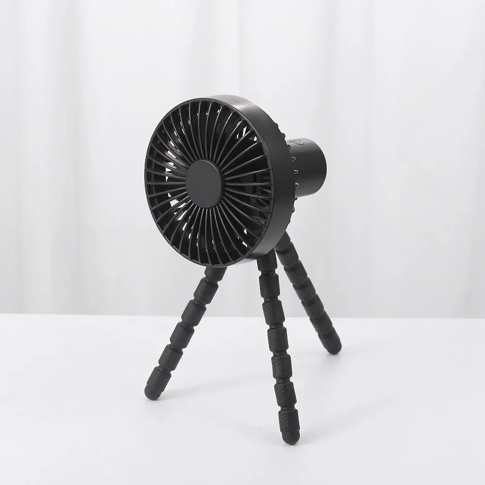 Black USB rechargeable desk fan with flexible tripod legs and an adjustable bending head on a wooden desk.