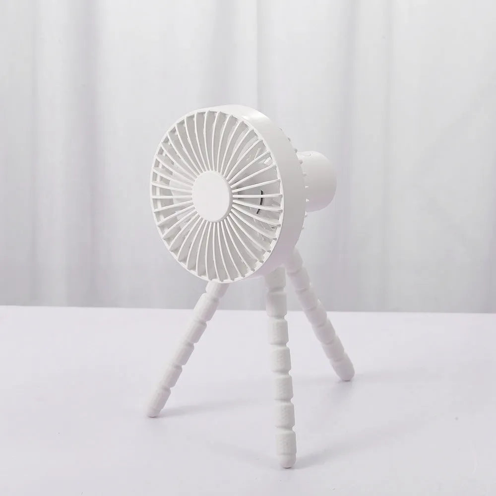 Black USB rechargeable desk fan with flexible tripod legs and an adjustable bending head on a wooden desk.