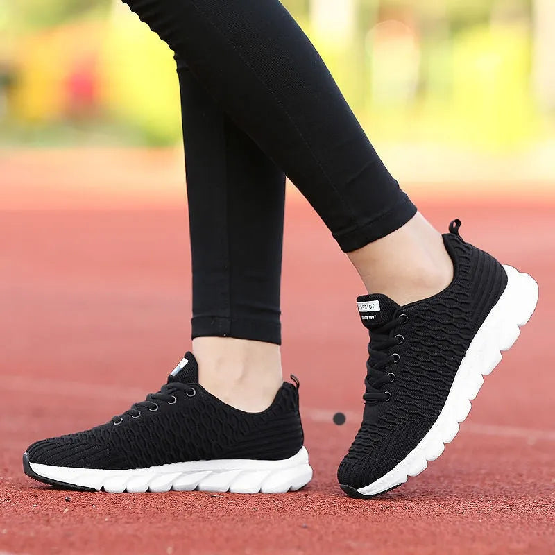 Women's running shoes in black, pink and white colours showing flyweave upper texture