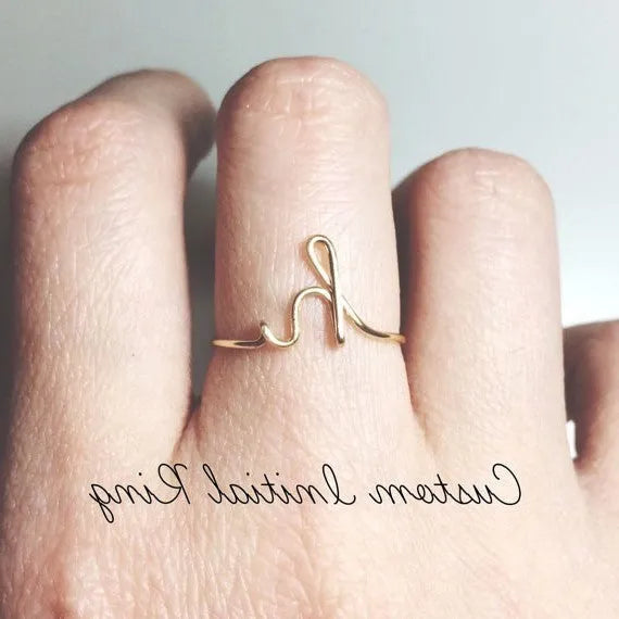 Gold coloured unisex alloy initial ring with letter A geometric shape on a flat surface