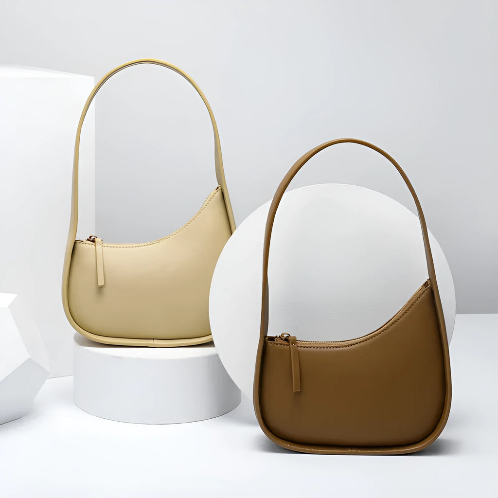 Small half moon shaped women's leather shoulder bag with a wide strap and soft handle.