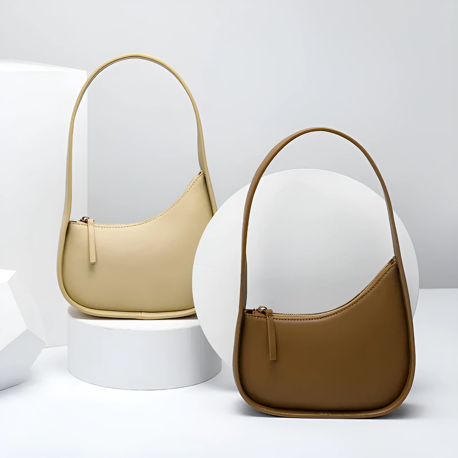 Small half moon shaped women's leather shoulder bag with a wide strap and soft handle.