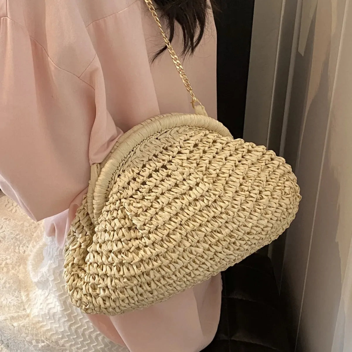 Shell-shaped straw shoulder bag with chain detailing and internal zipper pocket