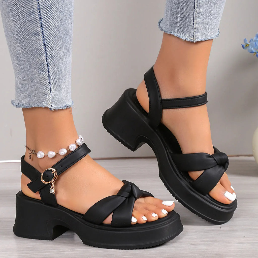 Women's black thick-heel slippers with a decorative skirt detail and button fastening.
