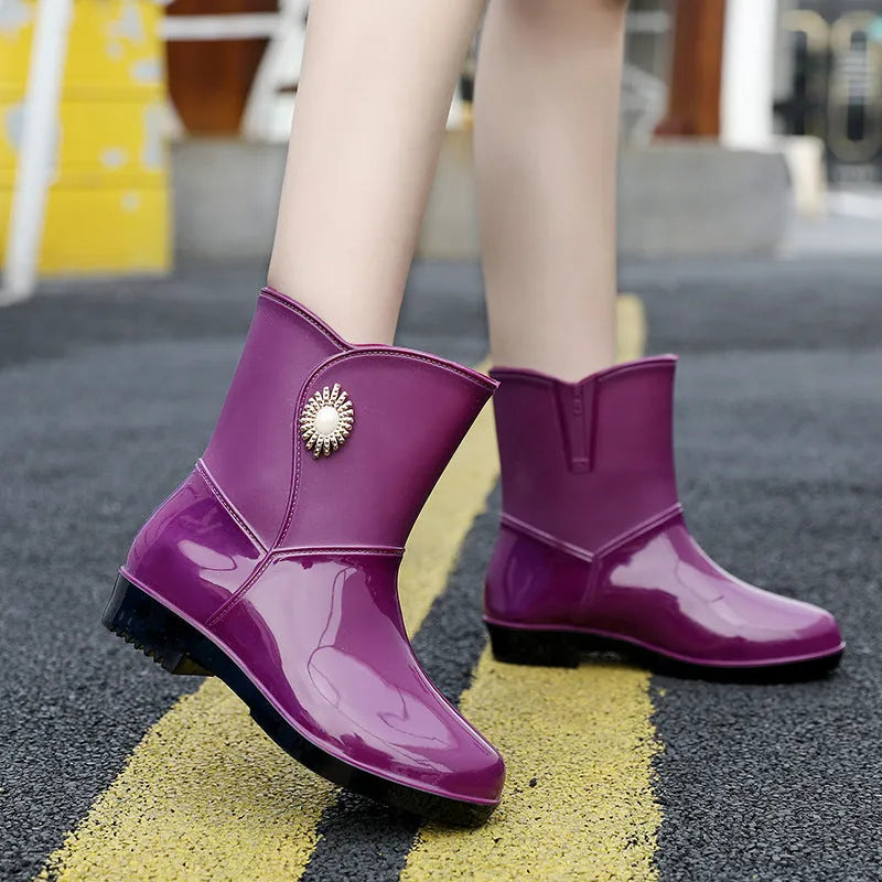 Women's purple PVC middle tube rain boots with a non-slip sole on a wet surface.