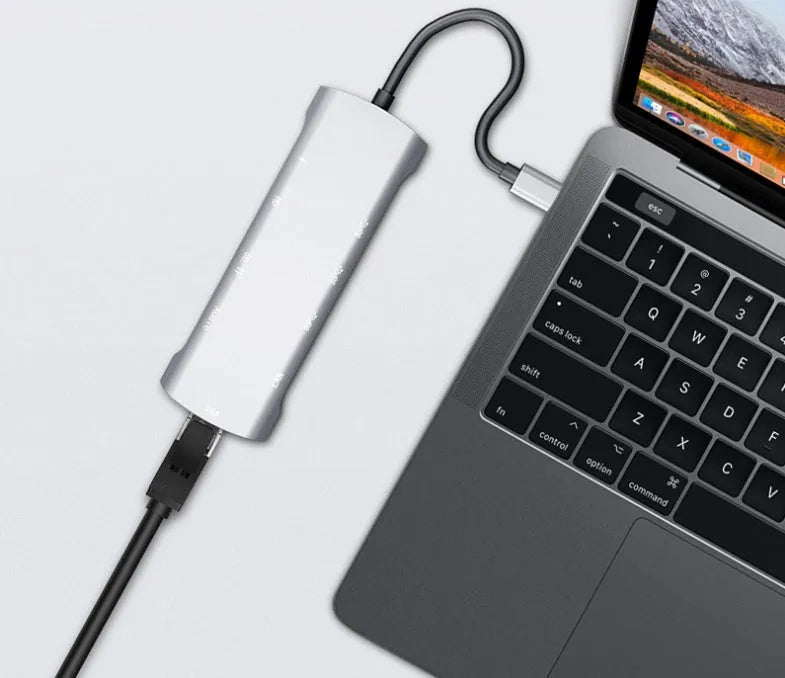 Grey aluminium USB-C docking station showing HDMI, VGA, USB 3.0, and USB-C PD ports with a short attached cable.