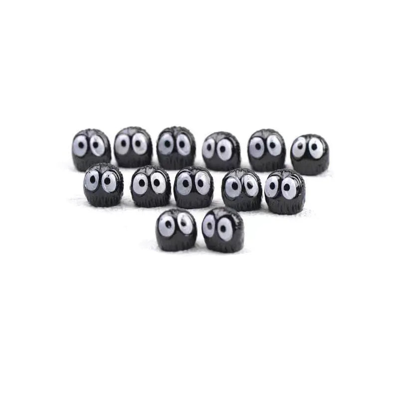 Small black resin cartoon coal briquette decoration next to a roll of traceless tape.