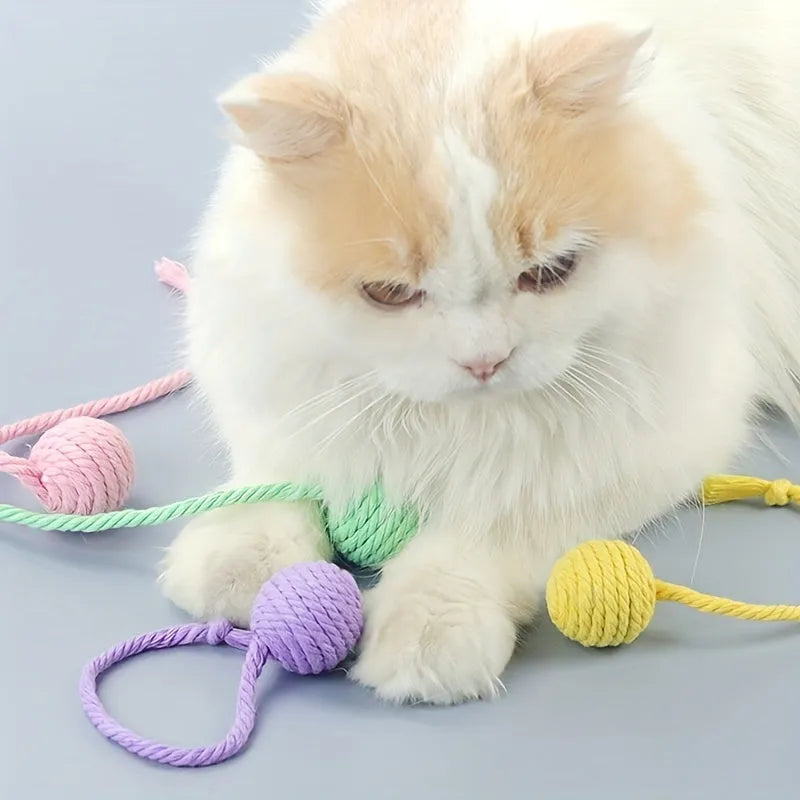 Green and pink plastic cat toy balls with ropes and internal bells.