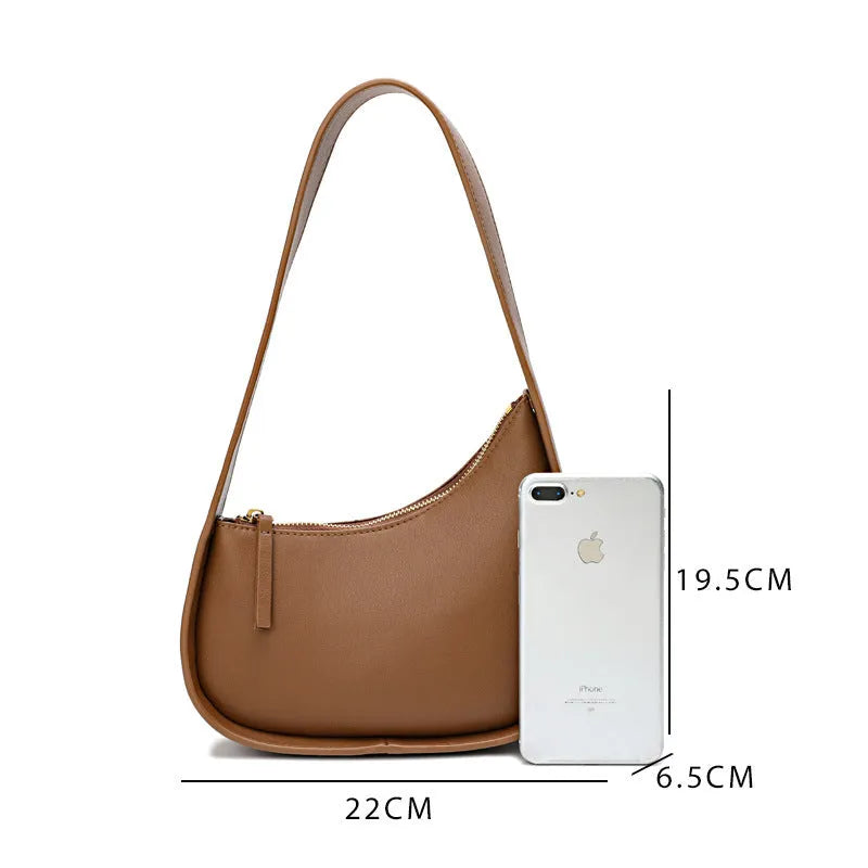 Small half moon shaped women's leather shoulder bag with a wide strap and soft handle.