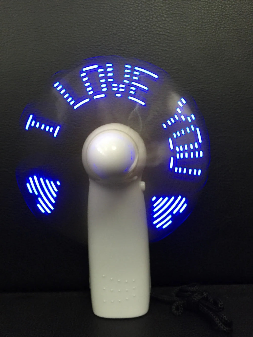 White handheld mini fan showing blue and red LED 'I Love You' pattern, held in hand.