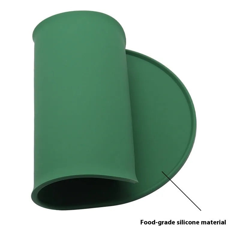 Green silicone placemat for cat bowls on a wooden floor.