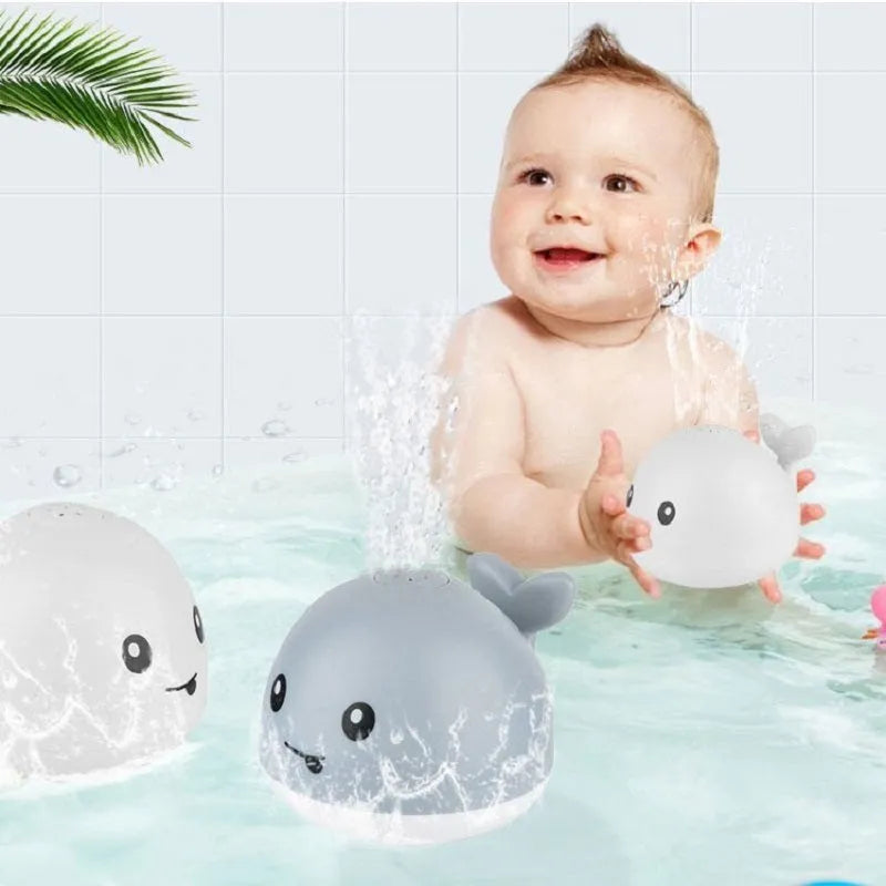 Electric whale bath toy with automatic water spray and flashing lights on a base