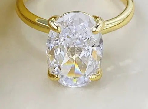 Oval women's ring with a four-claw setting on a silver band, showing gold and silver finish options.