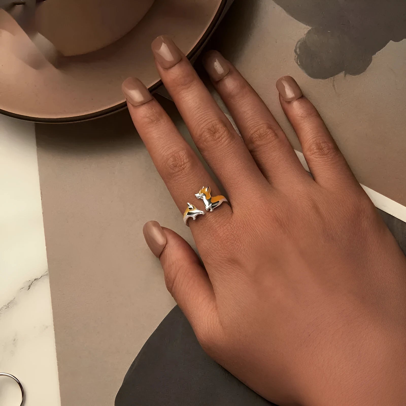 Silver-coloured cartoon corgi dog ring for women on a plain background.