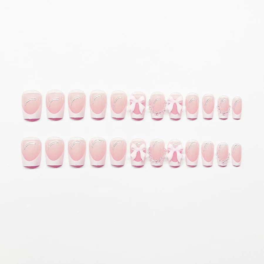 Short white French false nails with bow and tulip designs on a European square shape.