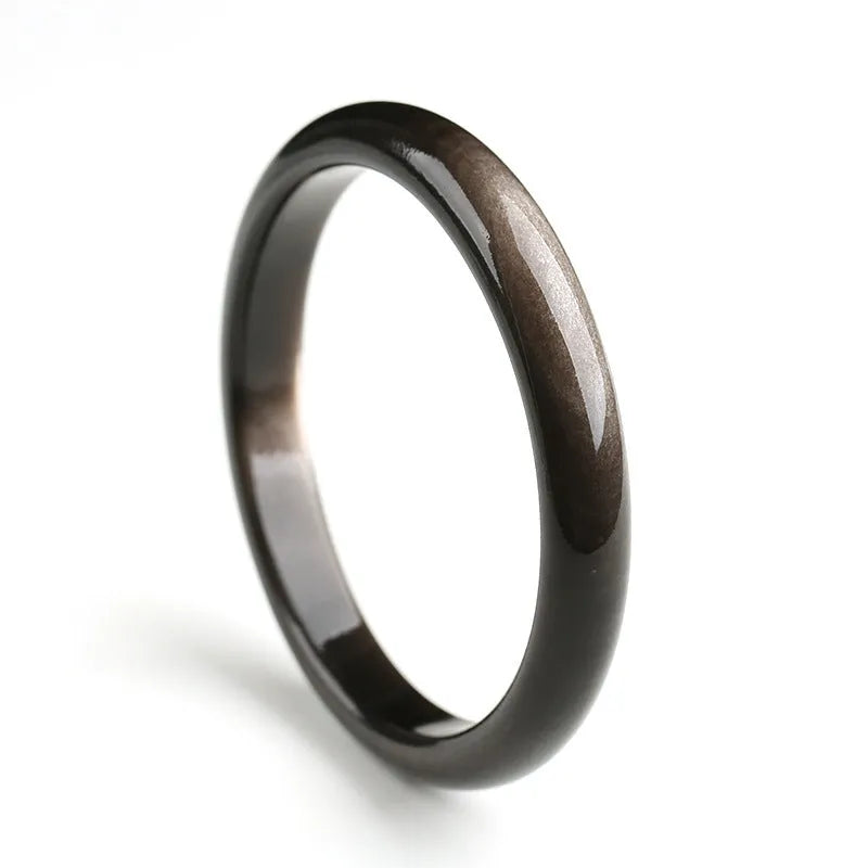 Obsidian cat's eye ethnic bracelet with geometric design on wrist, showing alloy and crystal construction.
