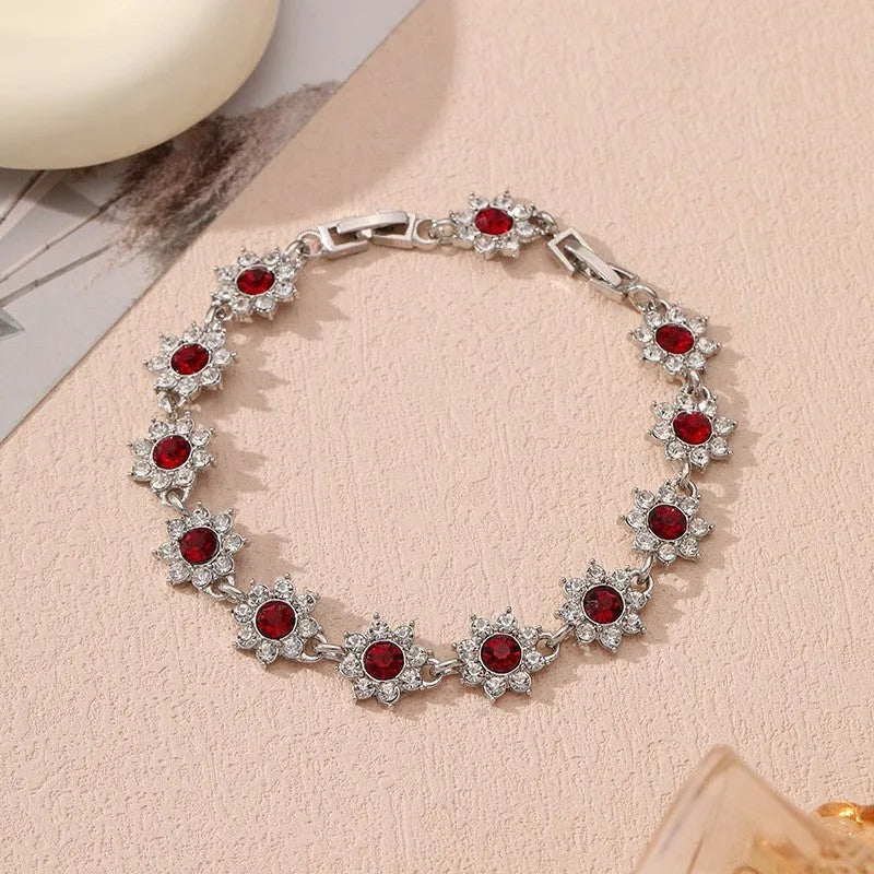 Electroplated zinc alloy bracelet with flower-shaped coloured gems in gold or silver tone.