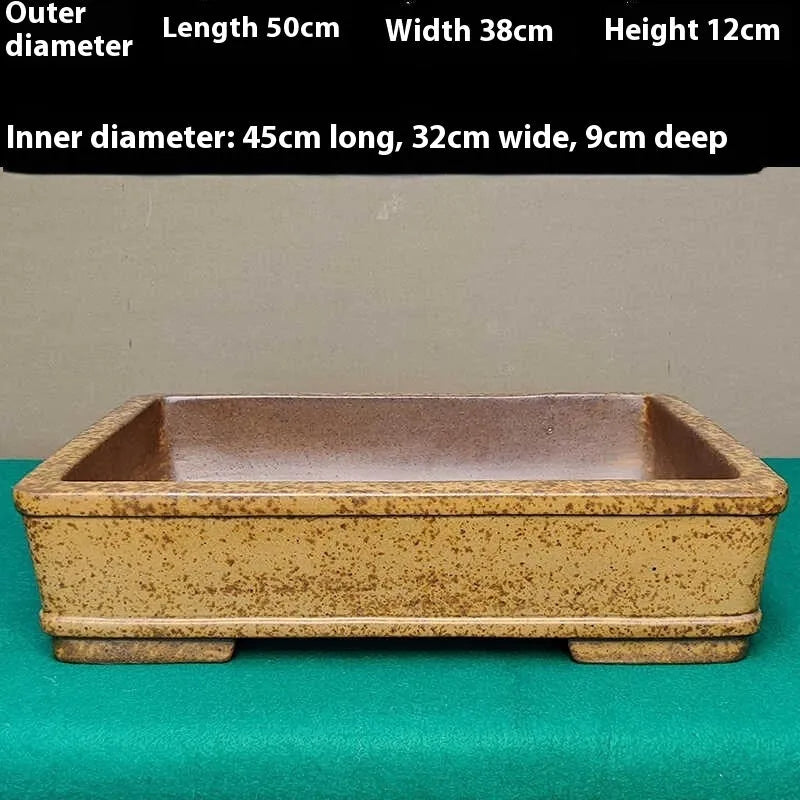Straight shallow rectangular Yixing Zisha flowerpot in purple sand clay on a ground surface.