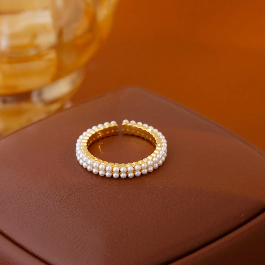 Gold geometric open ring for women with round pearls on a white background.