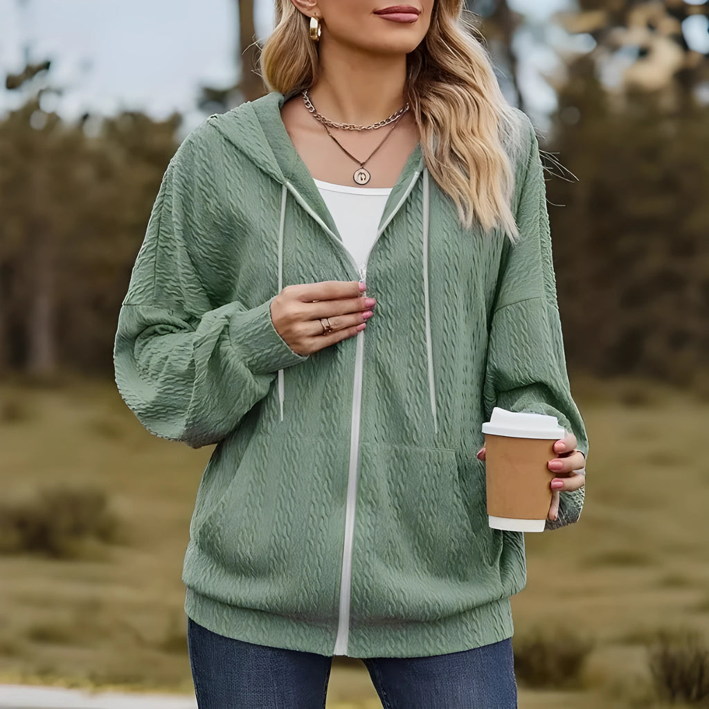 Green hooded zip-front sweatshirt coat on a hanger, showing loose fit and casual style.
