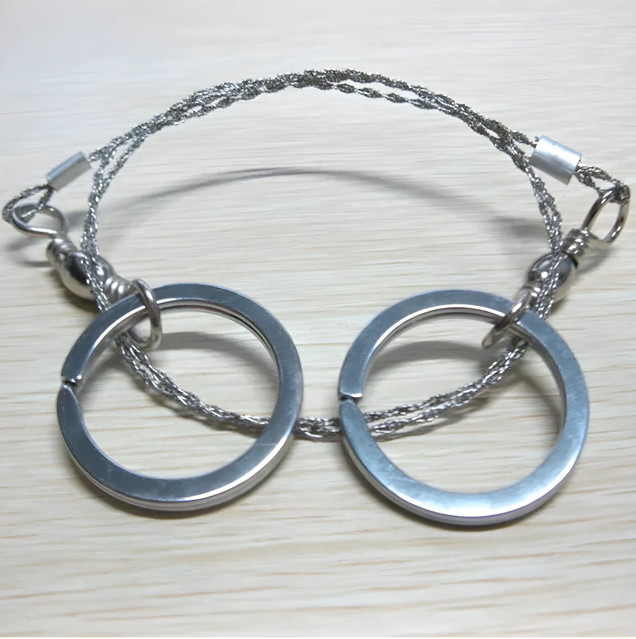 Stainless steel survival wire saw with pull rings, 55cm blade for outdoor wood cutting.