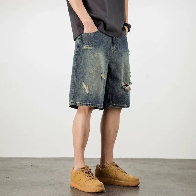 Man wearing blue retro loose-hole denim shorts with a straight leg cut on a casual background.