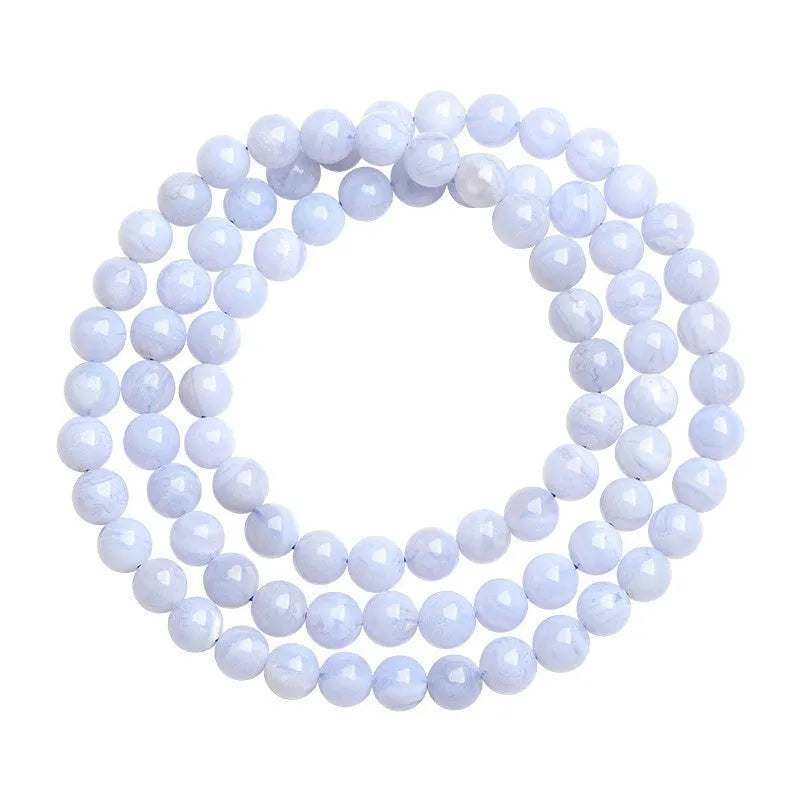 Close-up of a blue agate beaded bracelet with multi-circle pattern and scattered striped beads on a wrist.