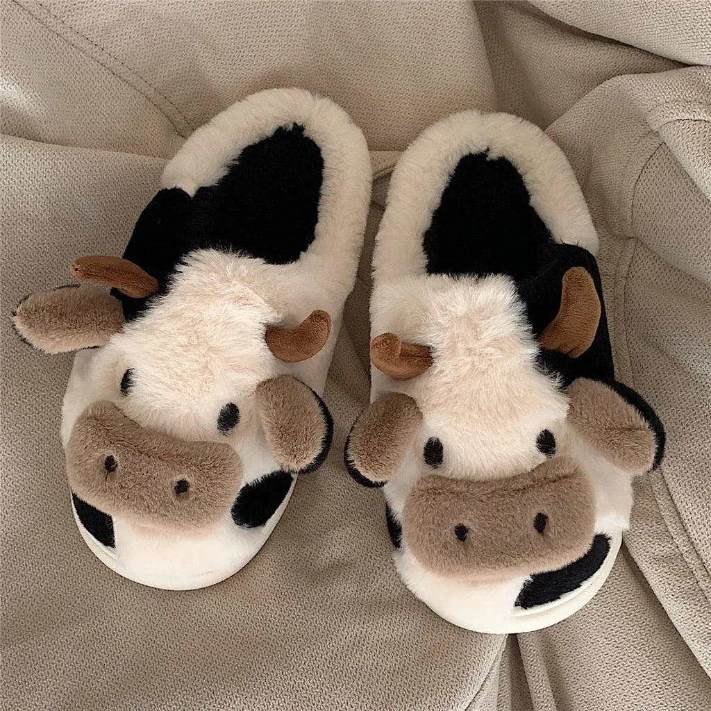 White and coffee coloured cow animal slippers for women with a plush exterior and non-slip sole.