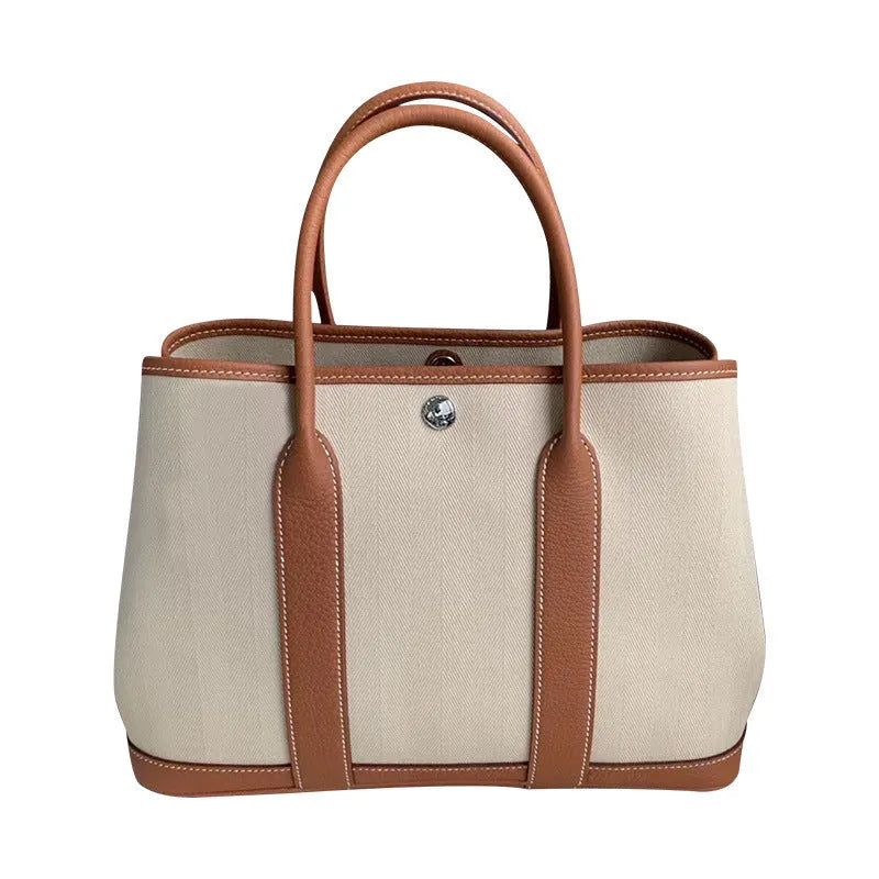 Women's canvas bucket tote bag with leather trim in black, showing internal zipper compartments