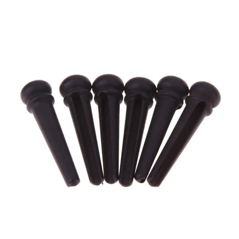 Set of six matt black ebony guitar bridge pins or string nails for acoustic guitar.