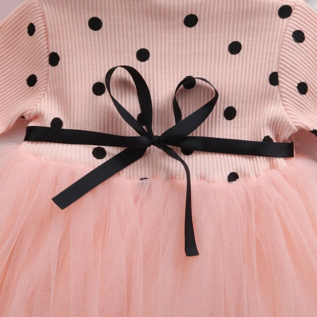 Baby girl in a long sleeve pink tutu dress with lace detailing on the sleeves.