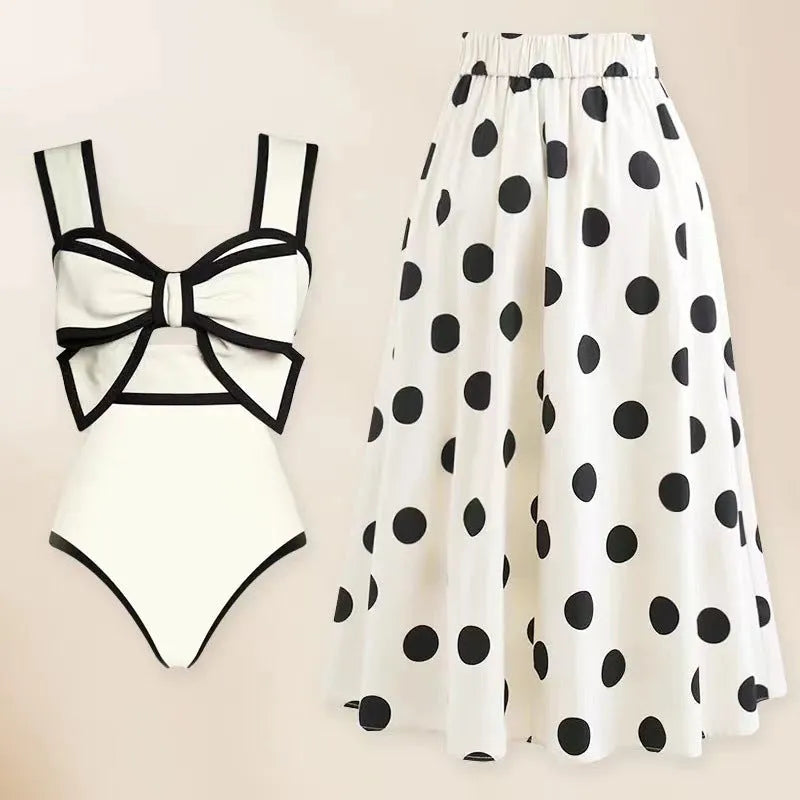 Women's black one-piece swimsuit with attached white skirt-style beach dress and a bow detail.