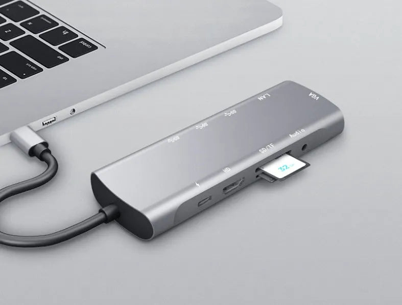 Grey aluminium USB-C docking station showing HDMI, VGA, USB 3.0, and USB-C PD ports with a short attached cable.