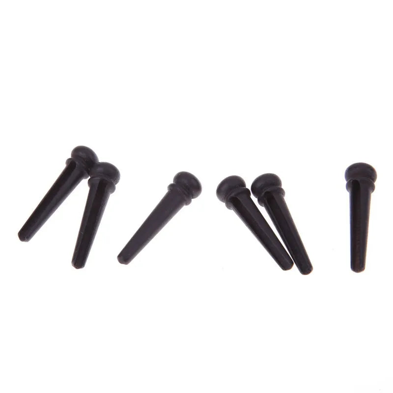 Set of six matt black ebony guitar bridge pins or string nails for acoustic guitar.