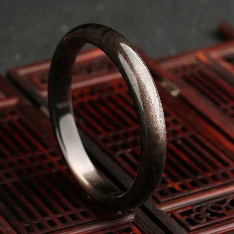 Obsidian cat's eye ethnic bracelet with geometric design on wrist, showing alloy and crystal construction.