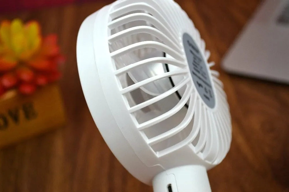 White ORICO FH1 portable USB rechargeable fan on a desk showing its compact size and three-speed button.