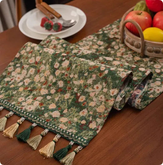 Long European-style retro table runner with decorative tassels in a floral design on a wooden table.
