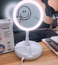 White foldable LED vanity mirror with USB charging port and double-sided storage compartment open on dressing table