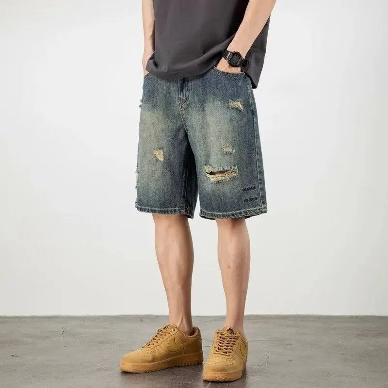 Man wearing blue retro loose-hole denim shorts with a straight leg cut on a casual background.